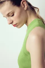 Top crop de tejido de punto color beige claro, con cuello redondo y manga sisa. Presenta acabados en rib en el cuello, sisas y bajo.