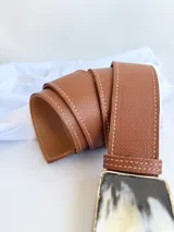 Cinto de cuero color tostado con hebilla rectangular de guampa con marco metálico. El broche suizo permite intercambiar la hebilla.