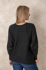 Buzo de punto color azul petróleo, con cuello redondo, mangas largas con puños ajustados y detalles de textura trenzada en la parte superior y el ruedo.