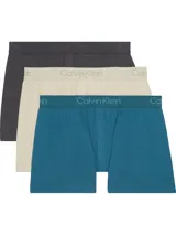 Pack de tres bóxers sueltos Calvin Klein, confeccionados en una mezcla suave de modal y elastano. Presentan un corte slim, talle medio, cierre de botones y cintura elástica con el logo distintivo de la marca. El set incluye un bóxer color gris oscuro, uno beige y uno azul petróleo.