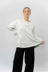 Buzo oversize de algodón frizado color beige, con cuello redondo, puños y cintura tejidos. Presenta un bordado tono sobre tono de Garfield en el frente.
