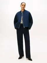 Campera bomber de satén azul marino con acabado repelente al agua y diseño acolchado. Presenta cuello estilo béisbol de punto canalé, cierre frontal de cremallera y logo de Tommy Hilfiger bordado en fuente script en el pecho.