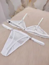 Conjunto de lencería compuesto por un corpiño triangular de microtul transparente con detalles de encaje floral y una tanga regulable a juego.