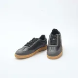 Zapatillas urbanas bajas de cuero sintético negro con puntera gris y suela marrón.