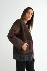 Saco tipo cardigan de punto gris con diseño bicolor, mangas largas acolchadas negras y bolsillos frontales también acolchados en color negro. Presenta cierre frontal con botones y terminaciones en tejido acanalado.