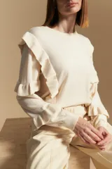 Sweater negro de manga larga, tejido suave y caída liviana, con volados en el delantero y mangas. Silueta recta.