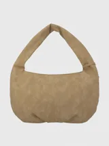 Cartera tipo hobo de Hush Puppies en color taupe, confeccionada en material con textura gamuzada. Presenta un diseño de media luna con tachas metálicas decorativas en los laterales y la base, asa única integrada y un dije colgante con el logo de la marca.