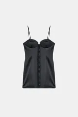 Vestido corto satinado negro con escote corazón, tirantes finos y cierre frontal con corchetes metálicos.