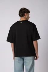 Remera de corte oversize color beige, con cuello redondo y etiqueta decorativa pequeña en el ruedo inferior.