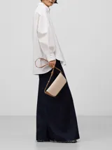 Riñonera de piel bovina en dos tonos: base marrón y solapa color crema. Tiene un compartimento principal con cierre magnético oculto bajo la solapa y un bolsillo interior. Incluye un asa larga regulable para llevar cruzada o como riñonera.