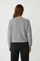 Sweater de algodón gris, holgado, con cuello a la base y mangas largas.