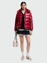 Campera puffer de nylon brillante en color rojo, con capucha desmontable, cierre frontal y bolsillos laterales. Presenta un diseño acolchado horizontal y logo de la marca en la manga.