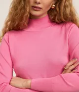 Blusa de tricot ligera en color rosado, de manga larga y cuello alto, con detalle de pequeño bordado en el pecho.