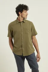 Camisa sport de manga corta, confeccionada en una mezcla de lino y algodón. Presenta cuello clásico, cierre frontal con botones de coco y un bolsillo aplicado en el pecho.