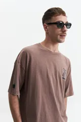 Remera gris oscuro con efecto gastado, corte boxy, manga corta y cuello redondo. Estampado en el frente con diseño abstracto y texto 'mistral'.