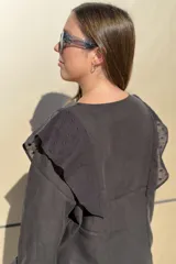 Blusa de algodón color bordó, con diseño de volados en los hombros, mangas largas con puños elásticos y corte holgado.