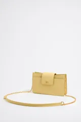 Bandolera amarilla de cuero con correa de cadena dorada y cierre con solapa con logo metálico.