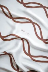 Pañuelo de seda blanco con estampado de líneas curvas en color verde lima, y texto sutil en la tela.