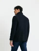 Sobretodo corto de paño en color azul marino, con cuello camisero, cierre frontal mediante botones y manga larga.