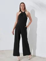 Enterito largo de crepe color rojo, con escote halter anudado y pierna ancha. Presenta bolsillos delanteros y abertura en la espalda con cierre invisible y botón.