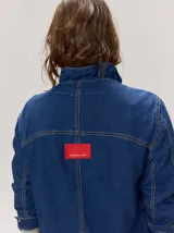 Campera de denim azul con cuello mao, cierre frontal con botones metálicos y presillas decorativas.