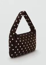 Bolso de hombro tipo baguette confeccionado en piel bovina color marrón oscuro, con diseño estructurado y superficie decorada con tachas metálicas plateadas distribuidas uniformemente. Cuenta con cierre superior y asa integrada.