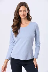 Remera básica de algodón color celeste melange, de manga larga y cuello redondo con detalle de pequeño botón decorativo en el ruedo.