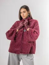 Chaqueta tipo capa de textura peluda en color bordó, con cuello mao y cierre frontal con botones grandes.
