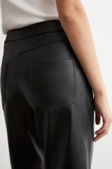 Pantalón recto de cuero sintético negro, con tiro medio, bolsillos laterales y costuras decorativas a la altura de las rodillas.