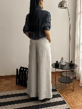 Pantalón de tiro alto con corte wide leg y diseño de pinzas frontales. Confeccionado en lino natural, presenta una silueta amplia y fluida con bolsillos laterales.