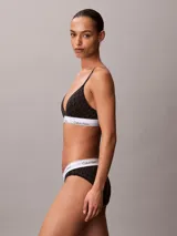 Bralette Calvin Klein de corte triangular, color negro con estampado geométrico de monogramas y banda elástica inferior blanca con el logotipo de la marca. Cuenta con tirantes finos ajustables.