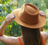 Sombrero marrón de ala ancha confeccionado en paño de lana afieltrada a mano, con cinta decorativa del mismo material alrededor de la copa.