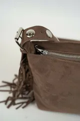Cartera de gamuza color marrón con flecos en los laterales y tira con ojales metálicos.