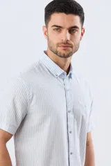 Camisa de manga corta confeccionada en mezcla de lino y algodón, con diseño de rayas verticales en tonos celeste y blanco. Cuenta con cuello camisero, botonadura frontal y bordado sutil en el pecho.