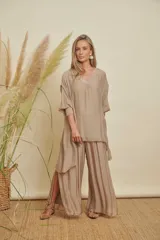 Conjunto de dos piezas color beige, compuesto por una blusa holgada de manga 3/4 con escote en V y detalles de lentejuelas, y un pantalón palazzo con aberturas laterales.