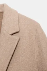 Abrigo de corte recto con cuello solapa de muescas, manga larga y cierre frontal con un solo botón.