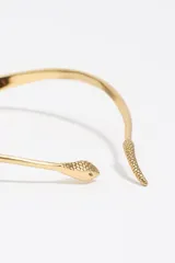 Collar rígido tipo gargantilla de la marca Bimba y Lola, con diseño en forma de serpiente. Presenta un acabado metálico dorado con textura de escamas en los extremos y cierre de bisagra en la parte posterior.