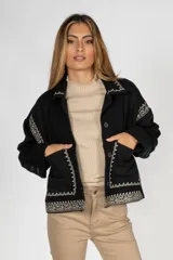 Sobrecamisa negra de paño con bordados geométricos en color crudo en el cuello, solapas, puños, bolsillos y bajo. Tiene cierre frontal con botones y bolsillos laterales.