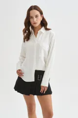 Camisa de viscosa blanca de corte holgado, con mangas largas, cuello camisero, cierre frontal con botones y detalle de bolsillo otonado en el pecho.