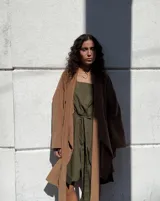 Collar con dije colgante de forma orgánica e irregular, acabado dorado, suspendido de un cordón negro de algodón natural.