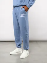 Pantalón jogger de felpa sin frisa, color gris claro melange, con logo bordado de Umbro en azul oscuro en el muslo izquierdo y puños elásticos en los tobillos.