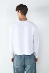 Camiseta de manga larga con corte boxy y cuello redondo, confeccionada en 100% algodón. Presenta una silueta holgada y diseño minimalista.