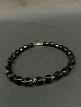 Collar de piedras naturales de ágata negra con diseño de cuentas facetadas en forma octogonal y detalles metálicos en gold filled 24k.