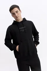 Canguro oversize de algodón, color negro, con capucha ajustable, bolsillo frontal tipo canguro y estampa sutil en el pecho.