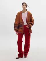 Pantalón de pana roja con corte holgado y tiro medio. Presenta una línea dorada a lo largo de la pierna.