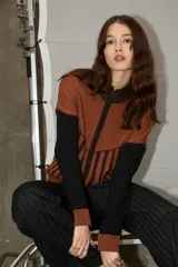 Campera de punto con cierre frontal, diseño bicolor en tonos bordó y rojo, con mangas largas y textura combinada de tejido liso y acanalado.