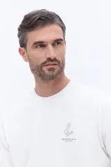 Remera de manga corta con textura, corte regular y cuello redondo. Presenta un diseño bordado en el pecho con motivos botánicos y el logo de la marca Brooksfield.