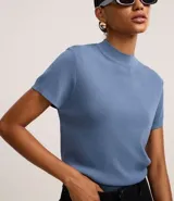 Blusa de punto color celeste, con cuello alto, manga corta y malla texturizada.