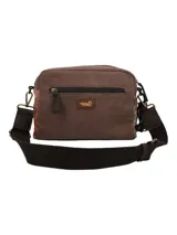 Cartera bandolera de diseño patchwork que combina paneles de tela marrón lisa con secciones de tejido estampado con motivos geométricos y florales. Cuenta con cierre de cremallera en el compartimento principal, bolsillo trasero, correa ajustable y desmontable, y un detalle de borlas decorativas con dijes en uno de los laterales.