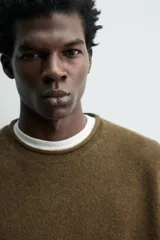 Jersey de punto de lana con corte regular fit, cuello redondo y manga larga. Presenta un diseño minimalista con acabados enrollados en cuello, puños y ruedo.